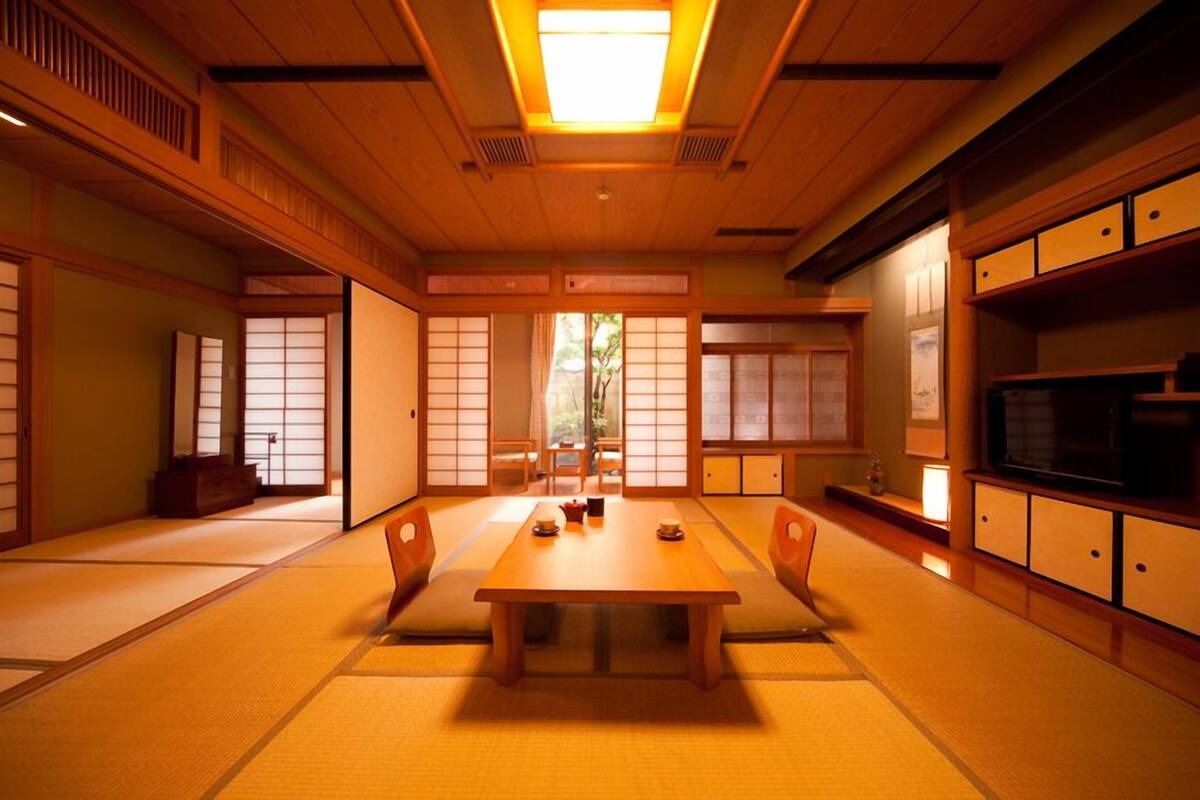 A traditional Japanese room with tatami flooring, a low wooden table, sliding doors, and a television.