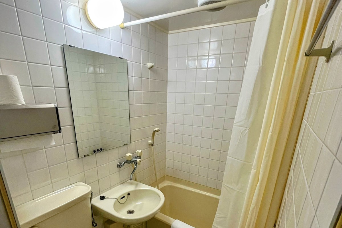 Ein Badezimmer mit Toilette, Waschbecken, Spiegel und Duschvorhang.