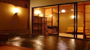Una habitación japonesa tradicional con suelo de tatami, puertas correderas y una mesa baja con sillas.