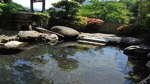 Un jardín japonés tradicional con un estanque, rocas y piedras para caminar.