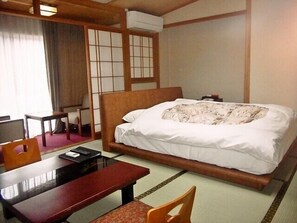 A hotel room with a bed, a desk, a chair, and a traditional Japanese sliding door. - Yumura Onsen Tomiya Ryokan (Shinonsen)