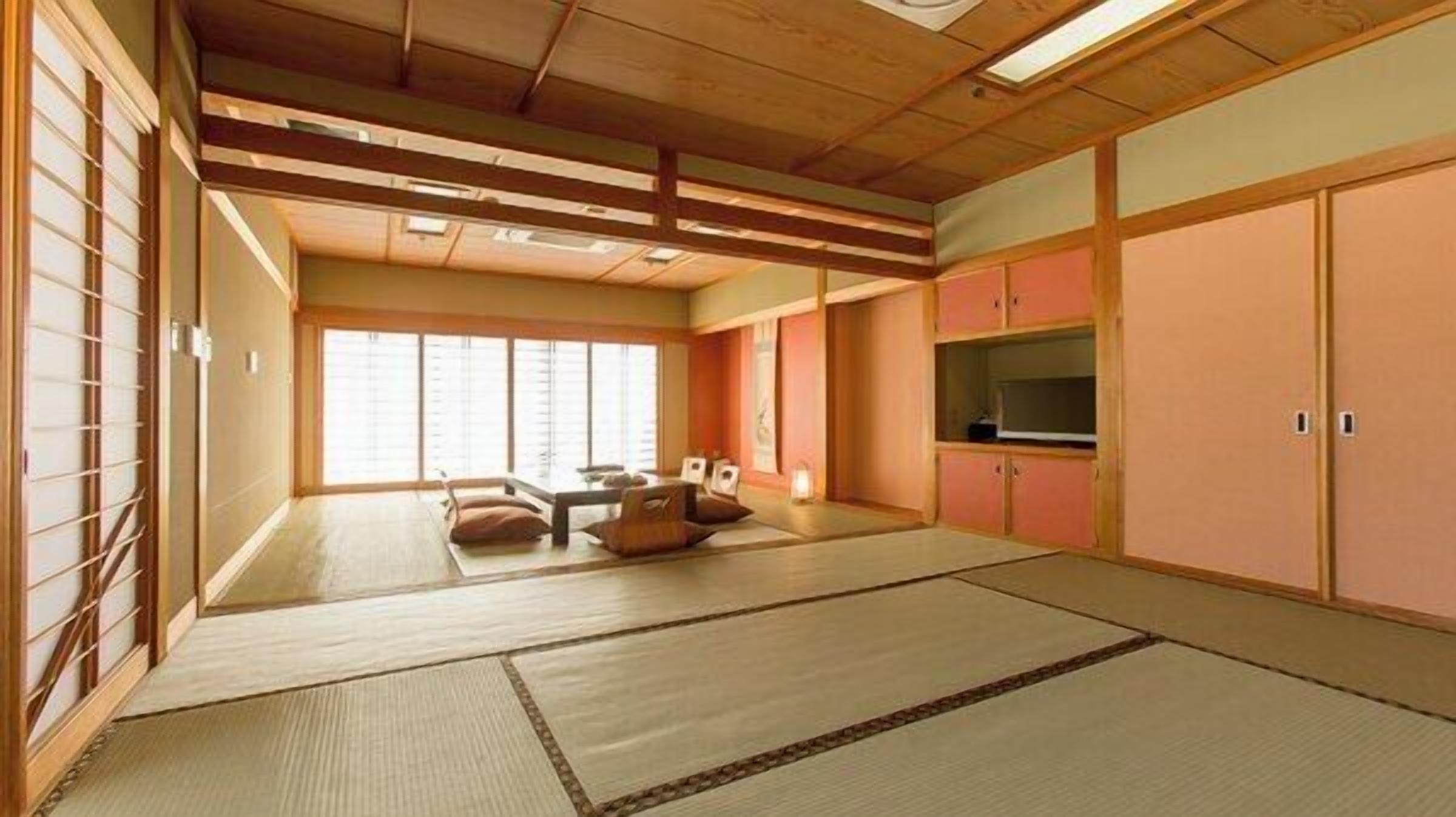Ein traditioneller japanischer Raum mit Tatami-Böden, Schiebetüren, einer niedrigen Decke und einem Fernseher.