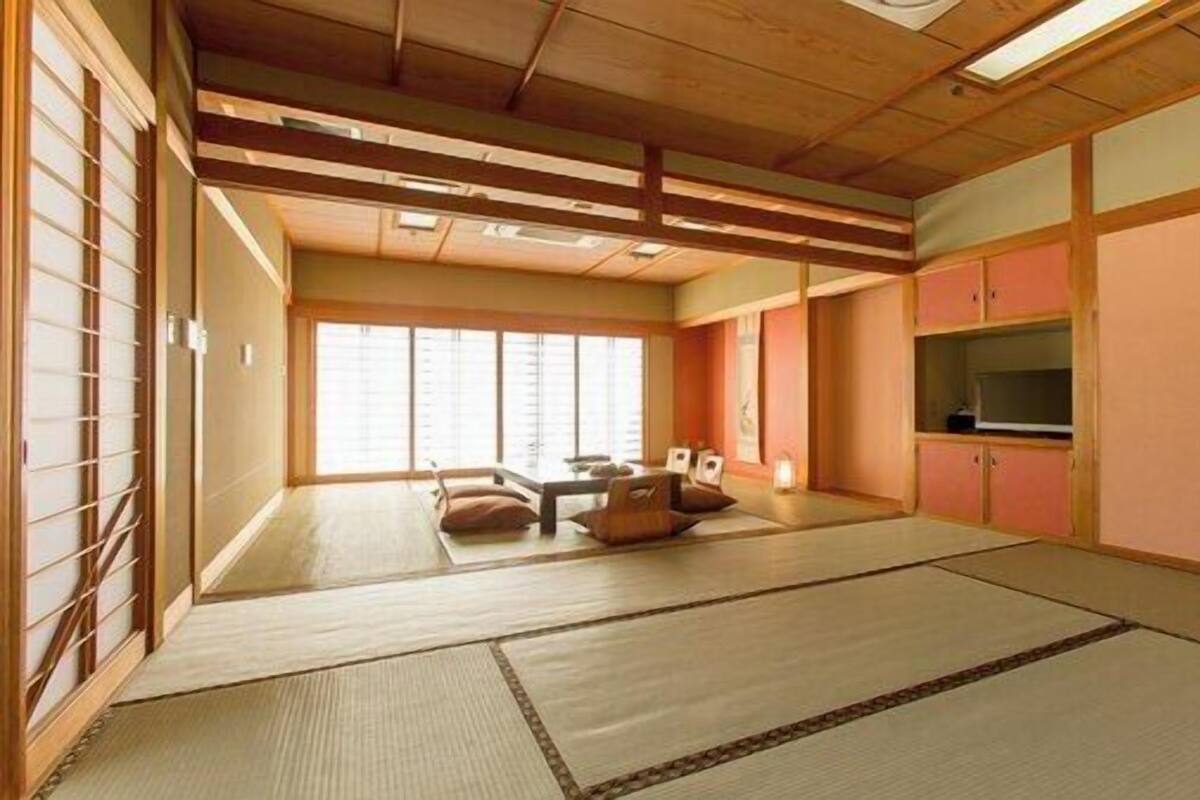 A traditional Japanese room with tatami flooring, sliding doors, a low ceiling, and a television.