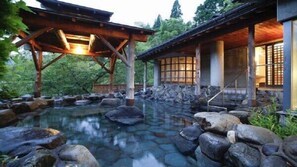 A traditional Japanese-style building with a stone pond, wooden structures, and a tranquil garden setting. - Yumura Onsen Tomiya Ryokan (Shinonsen)