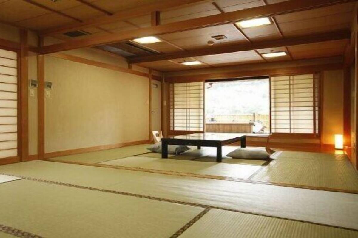 A traditional Japanese room with tatami flooring, sliding doors, and a low table with cushions.
