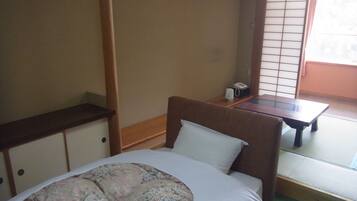 A room with a bed, a small table, and a window with a view.