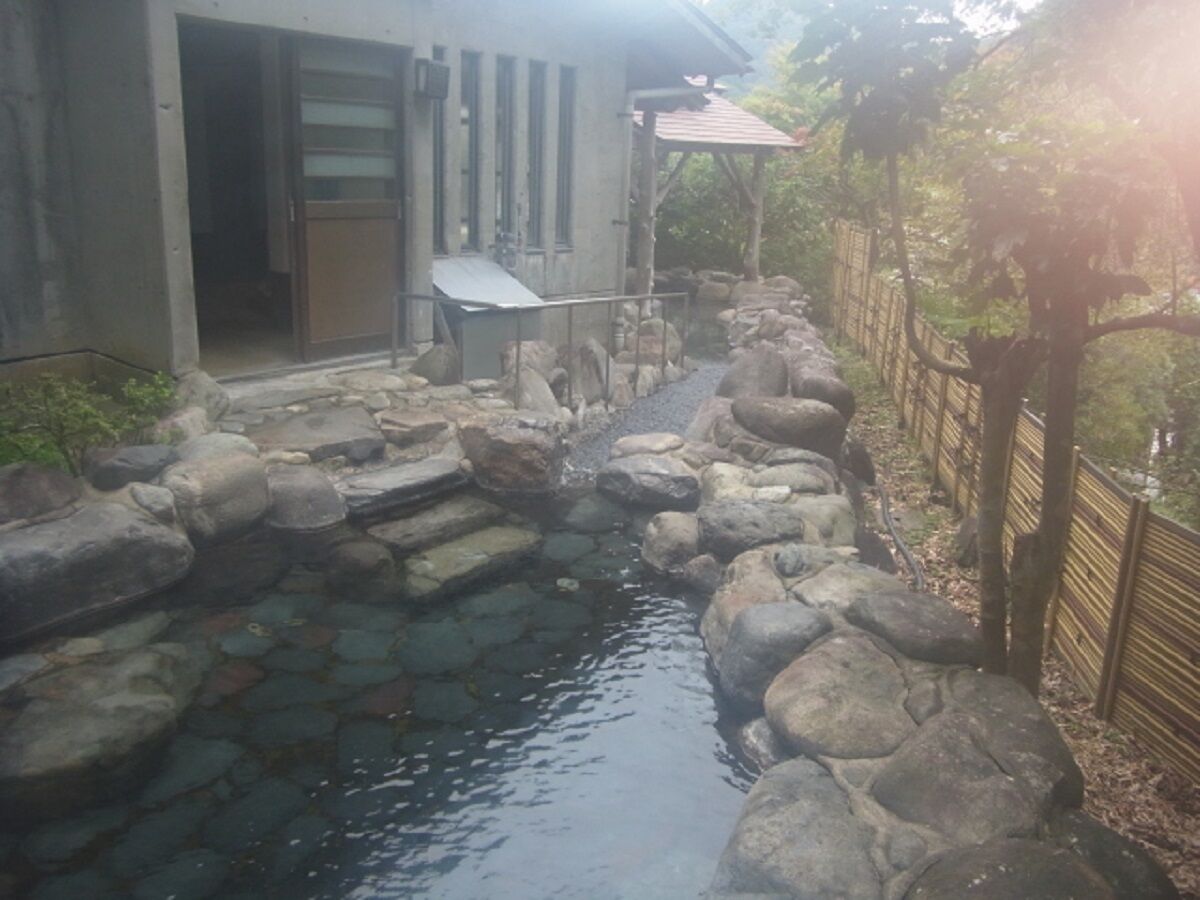 A stone water feature with a small stream, surrounded by rocks and a wooden fence.
