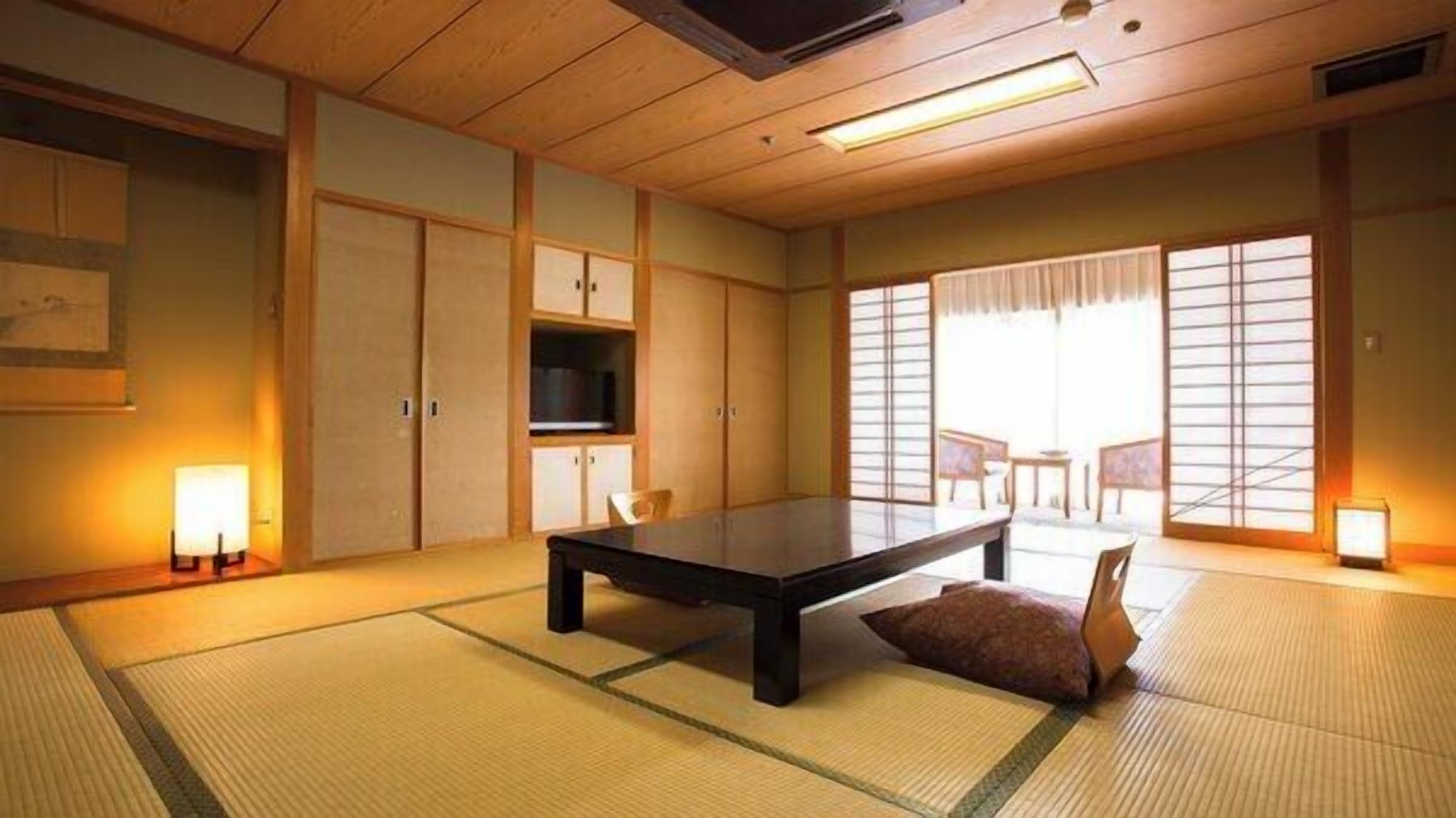 Ein traditioneller japanischer Raum mit Tatami-Bodenbelag, einem niedrigen Tisch, Schiebetüren und Blick durch einen Shoji-Bildschirm.