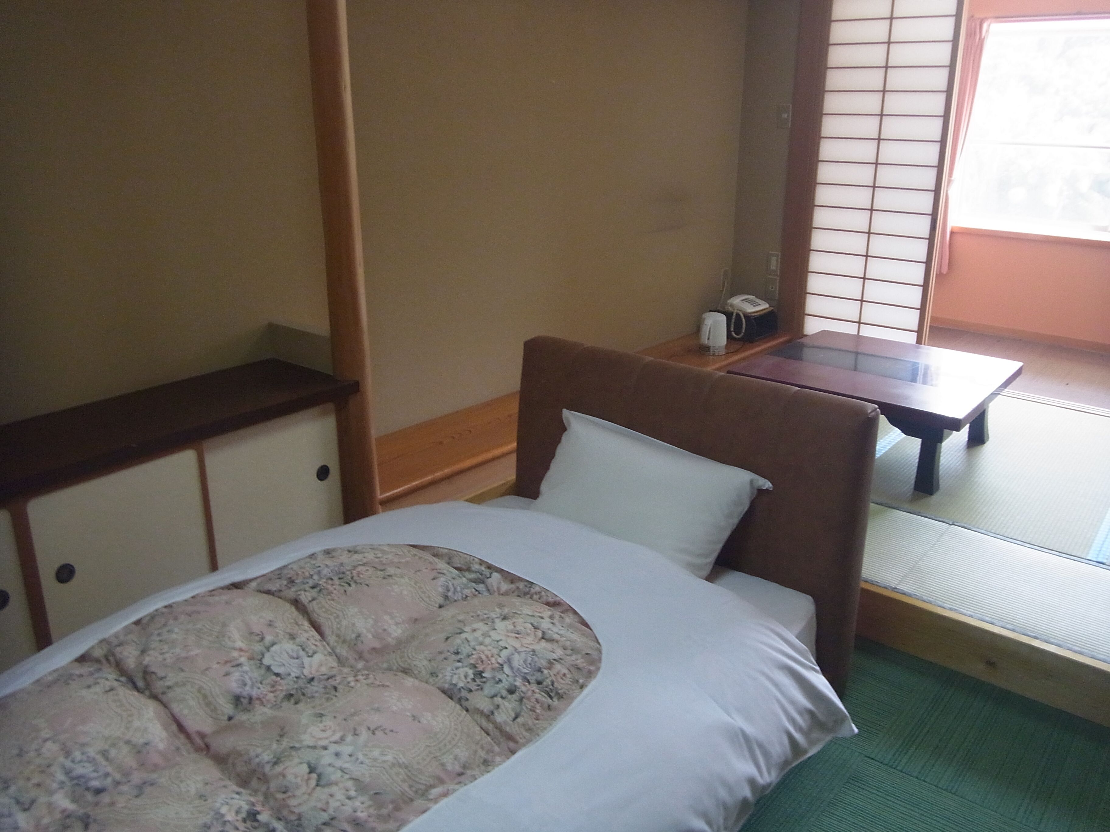 A room with a bed, a small table, and a window with a view.