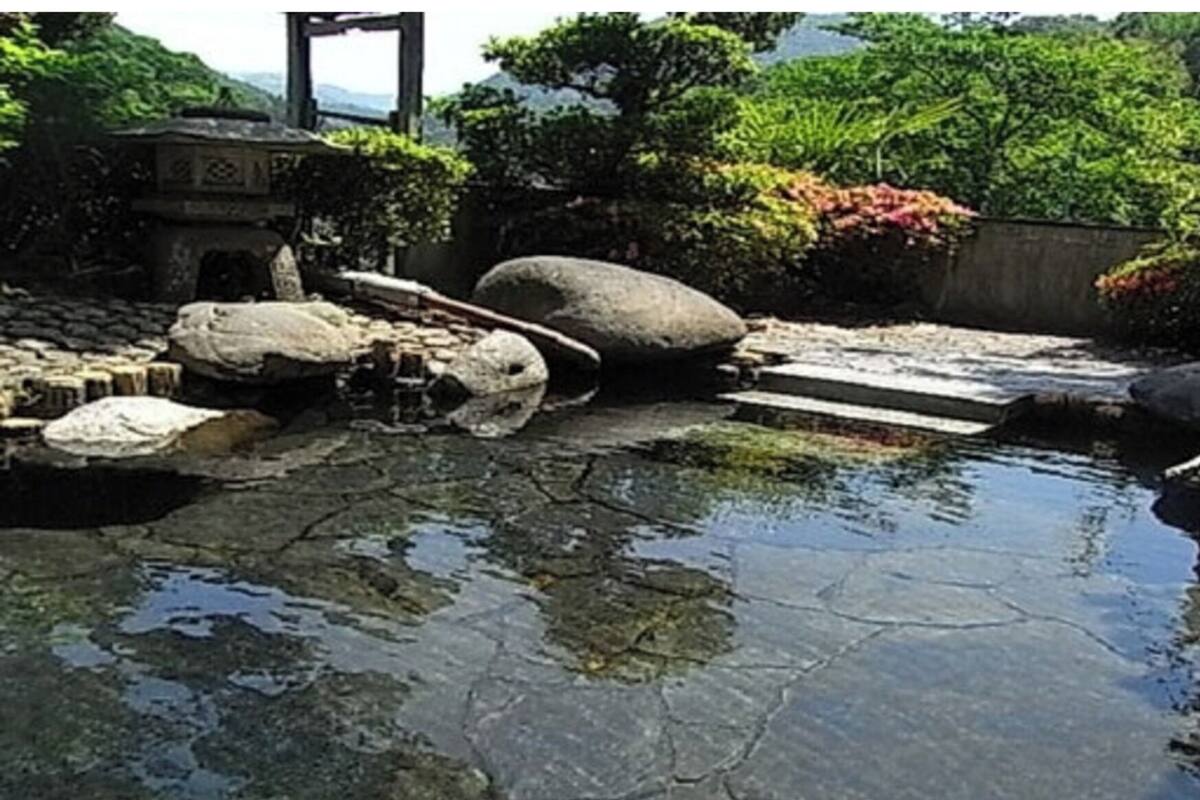 A serene garden with a small pond, large rocks, and a stone bridge.