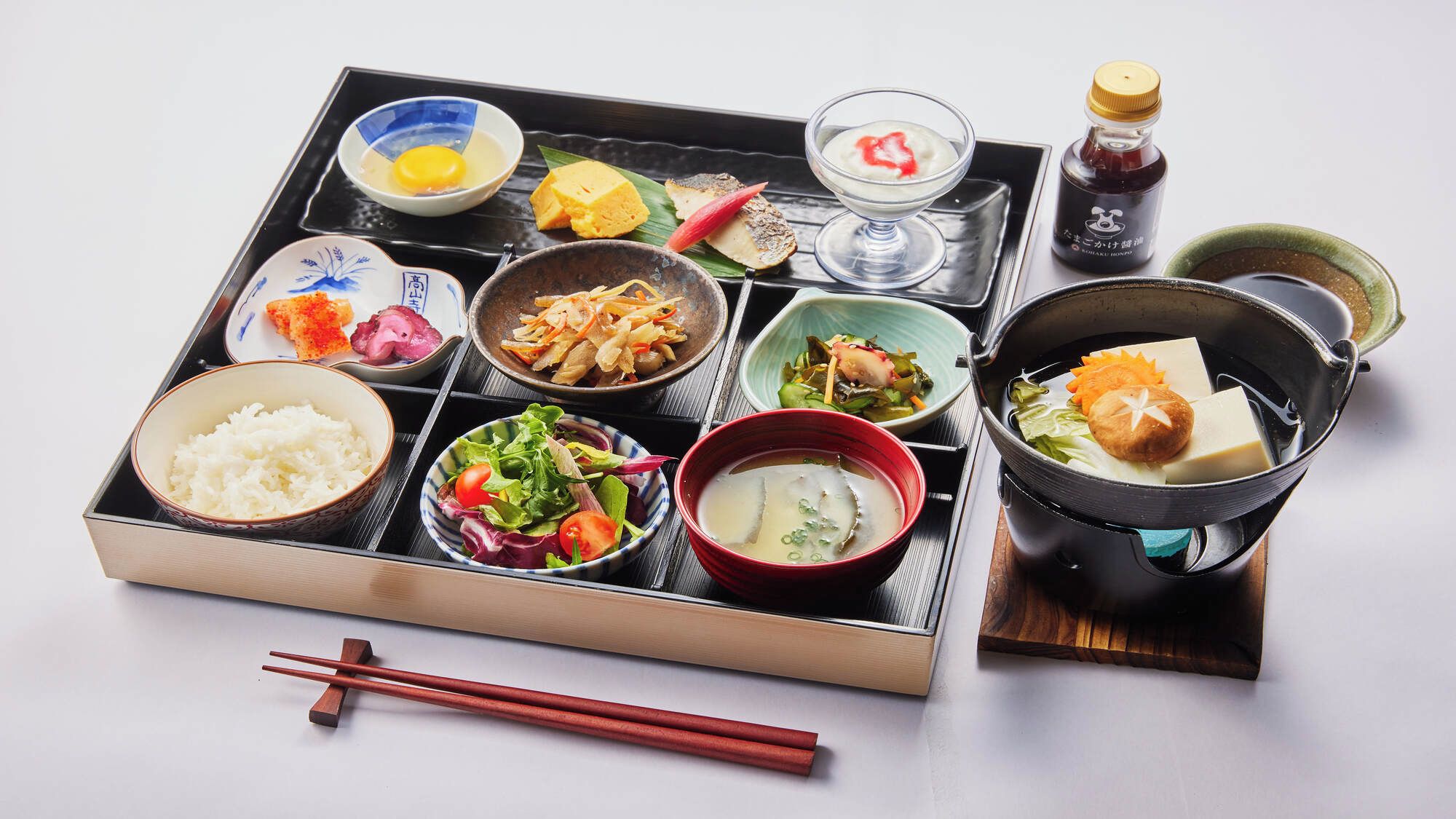 A traditional Japanese meal set with various dishes including rice, soup, and a pot of hot water.