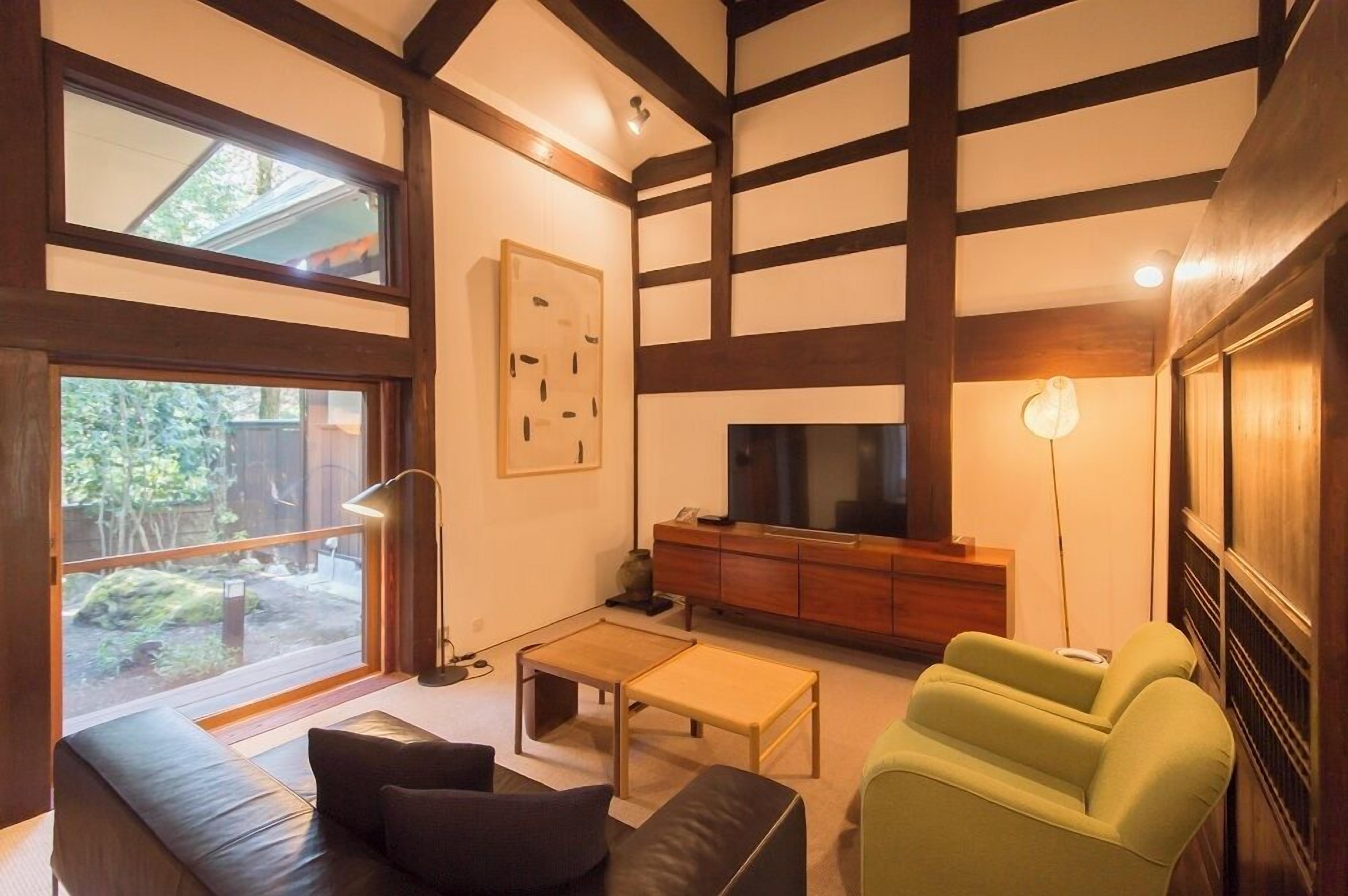 Una sala de estar moderna con un ventanal grande, un sofá, una mesa de centro, un televisor y un mueble.