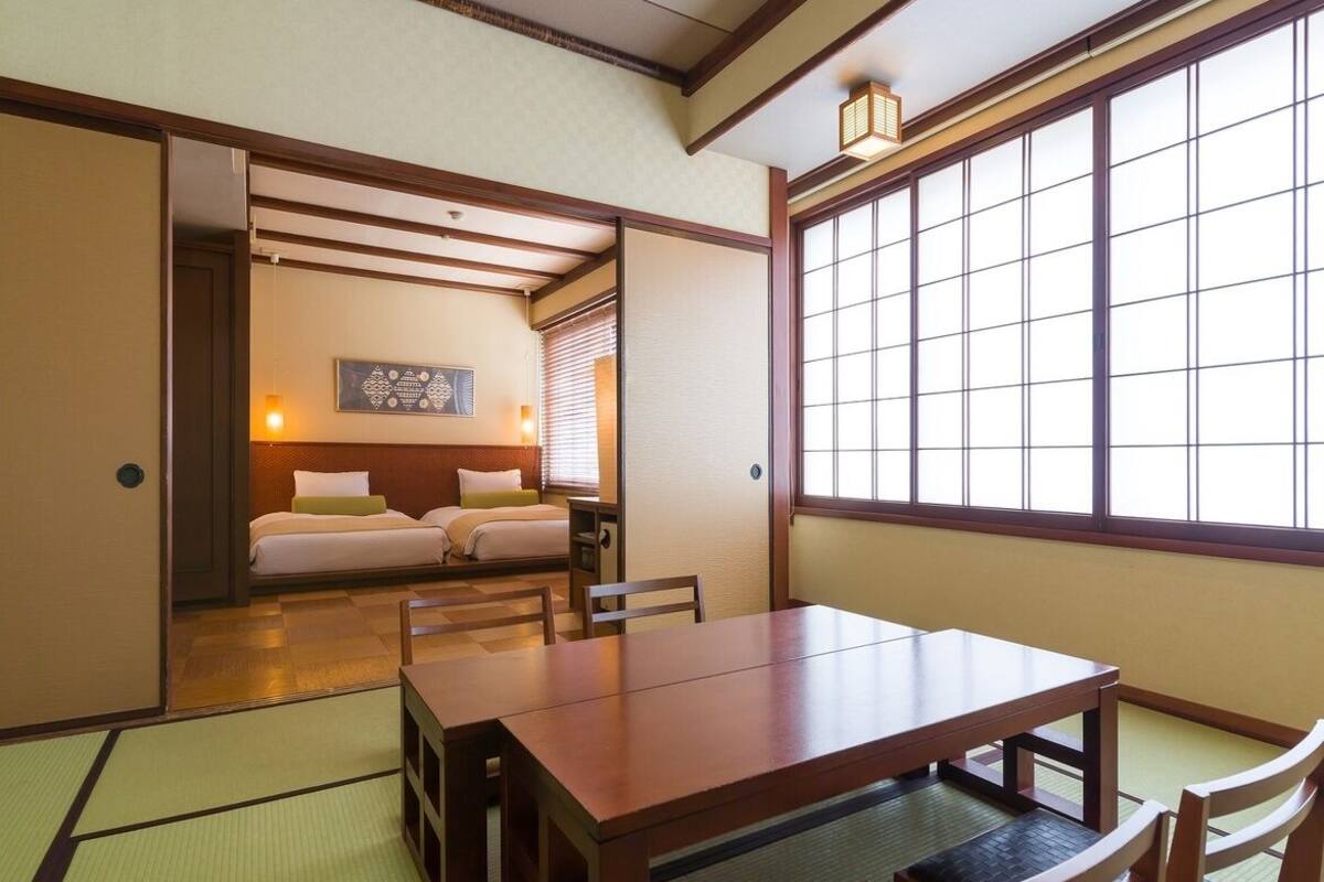 Ein traditioneller japanischer Raum mit Tatami-Bodenbelag, einem Holztisch und einem Bett mit Futon.