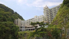 Un hotel moderno a più piani, situato su una collina ricca di vegetazione.