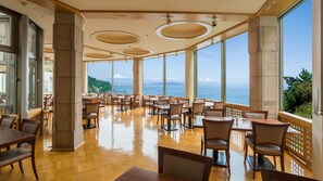A spacious indoor dining area with large windows offering a view of the sea and mountains. - Yaizu Onsen Yaizu Grand Hotel (Yaizu)