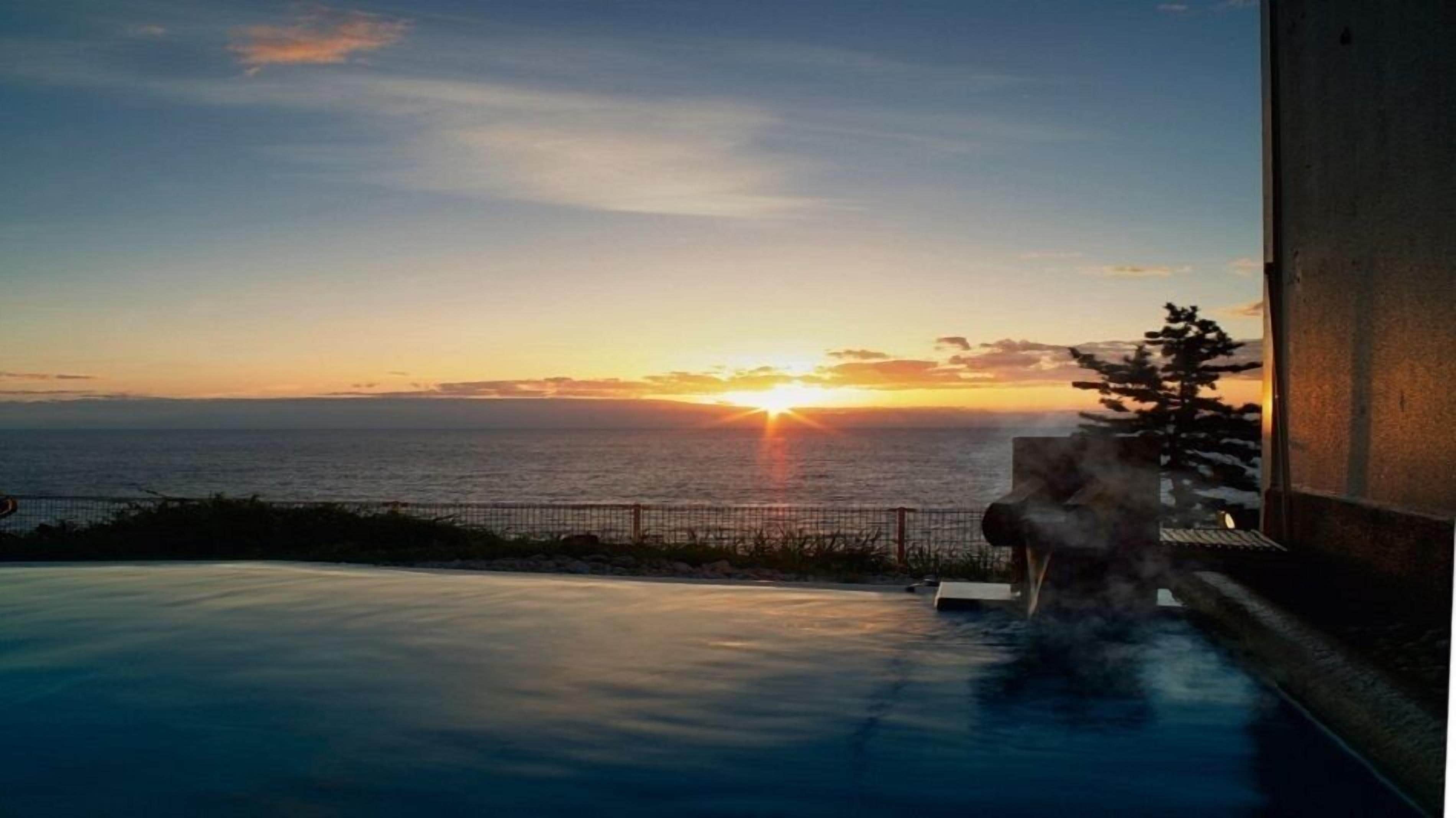 A pool with a sunset view over the ocean.