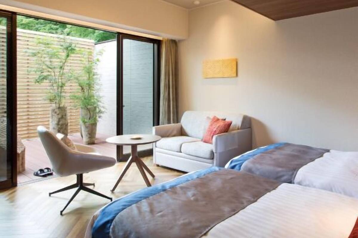 Ein modernes Hotelzimmer mit einem großen Bett, einer Couch, einem kleinen Tisch und einer Topfpflanze.