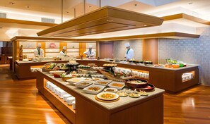Un buffet con diverse postazioni gastronomiche e chef al servizio.