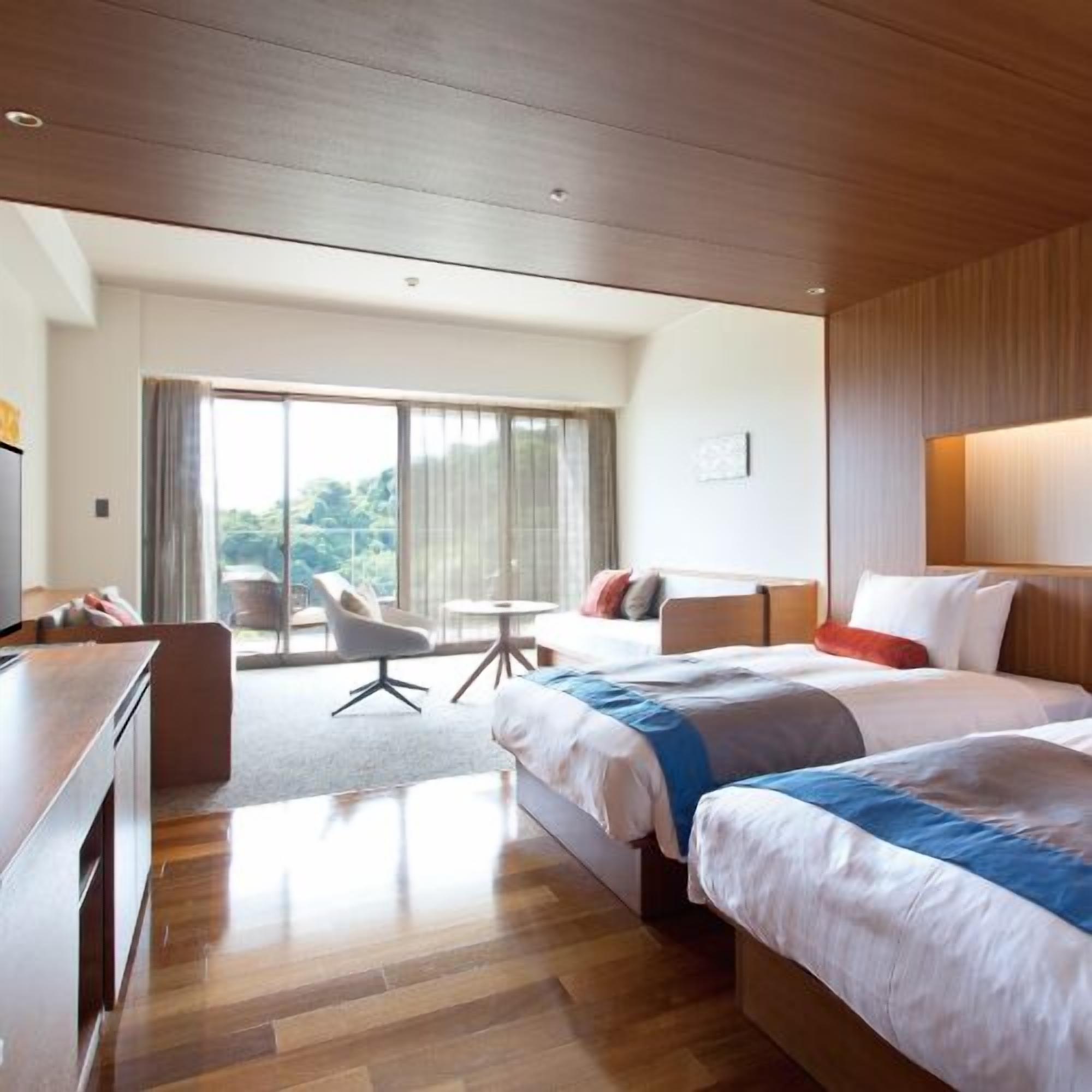 Une chambre d’hôtel équipée d’un lit, d’un bureau, d’une chaise et offrant une vue sur l’extérieur.
