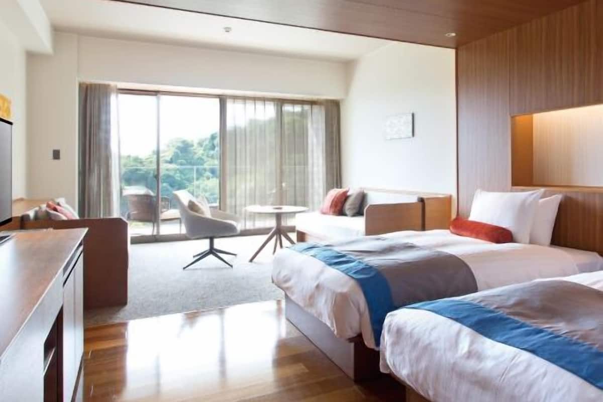 Ein Hotelzimmer mit Bett, Schreibtisch, Stuhl und Blick ins Freie.