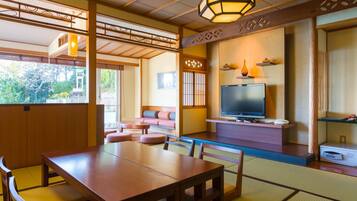 A traditional Japanese-style room with tatami flooring, a television, and a wooden table.