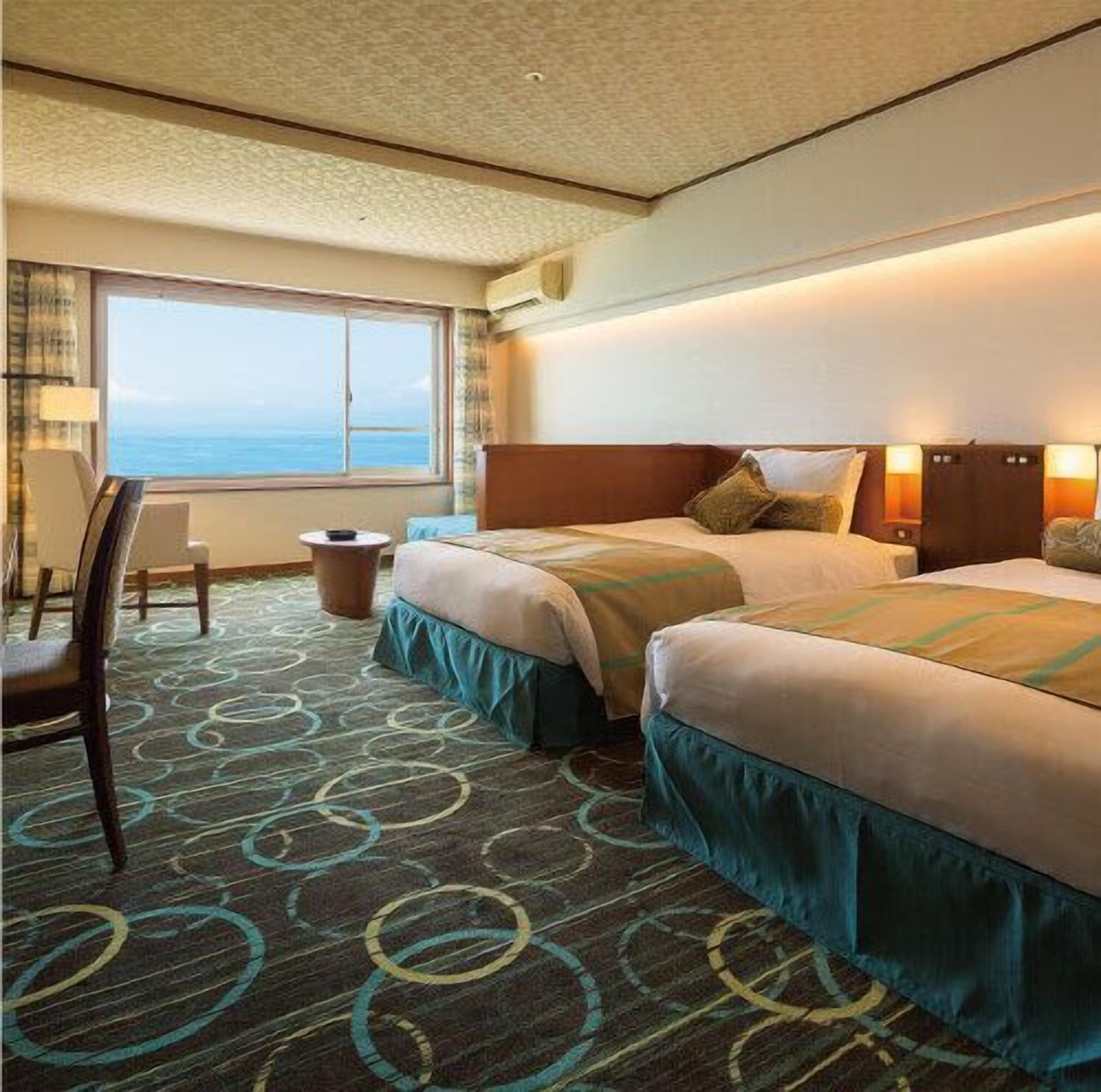 Camera d'albergo con due letti, una scrivania, una sedia e vista sull'oceano.