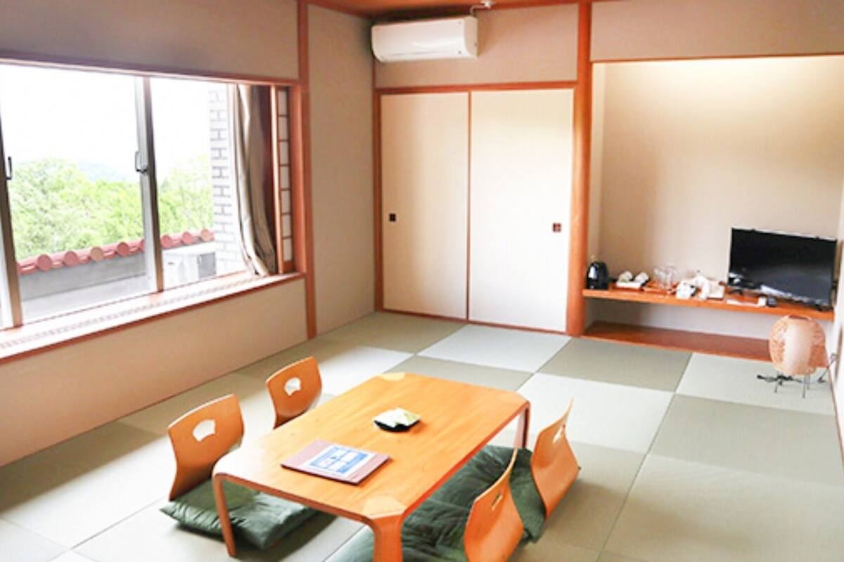 Une pièce comprenant une table à manger, des chaises, un téléviseur et une fenêtre donnant sur un paysage agréable.