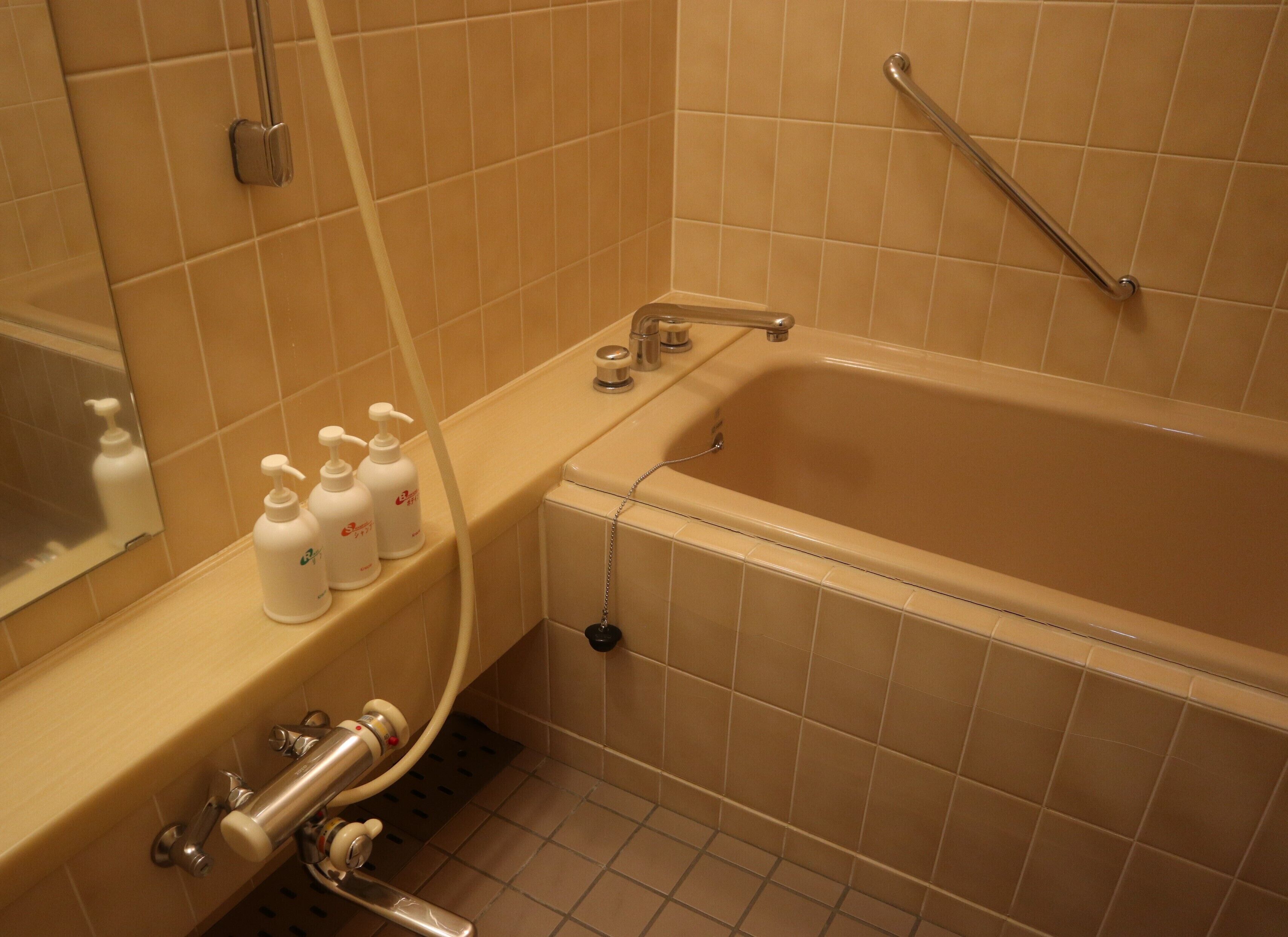 A bathroom with a bathtub, a shower, and a vanity with toiletries.
