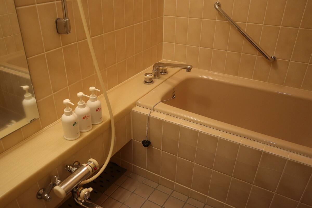 Une salle de bain équipée d’une baignoire, d’une douche et d’un meuble-lavabo avec des articles de toilette.
