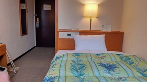 A hotel room with a bed, a nightstand, a lamp, a clock, and a door with a sign. - Plaza Hotel Sanda (Sanda)
