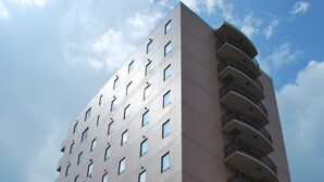 A high-rise building with multiple floors, balconies, and a clear sky in the background. - Plaza Hotel Sanda (Sanda)