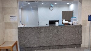 A reception desk with a granite counter, a clock, and a sign with instructions. - Plaza Hotel Sanda (Sanda)