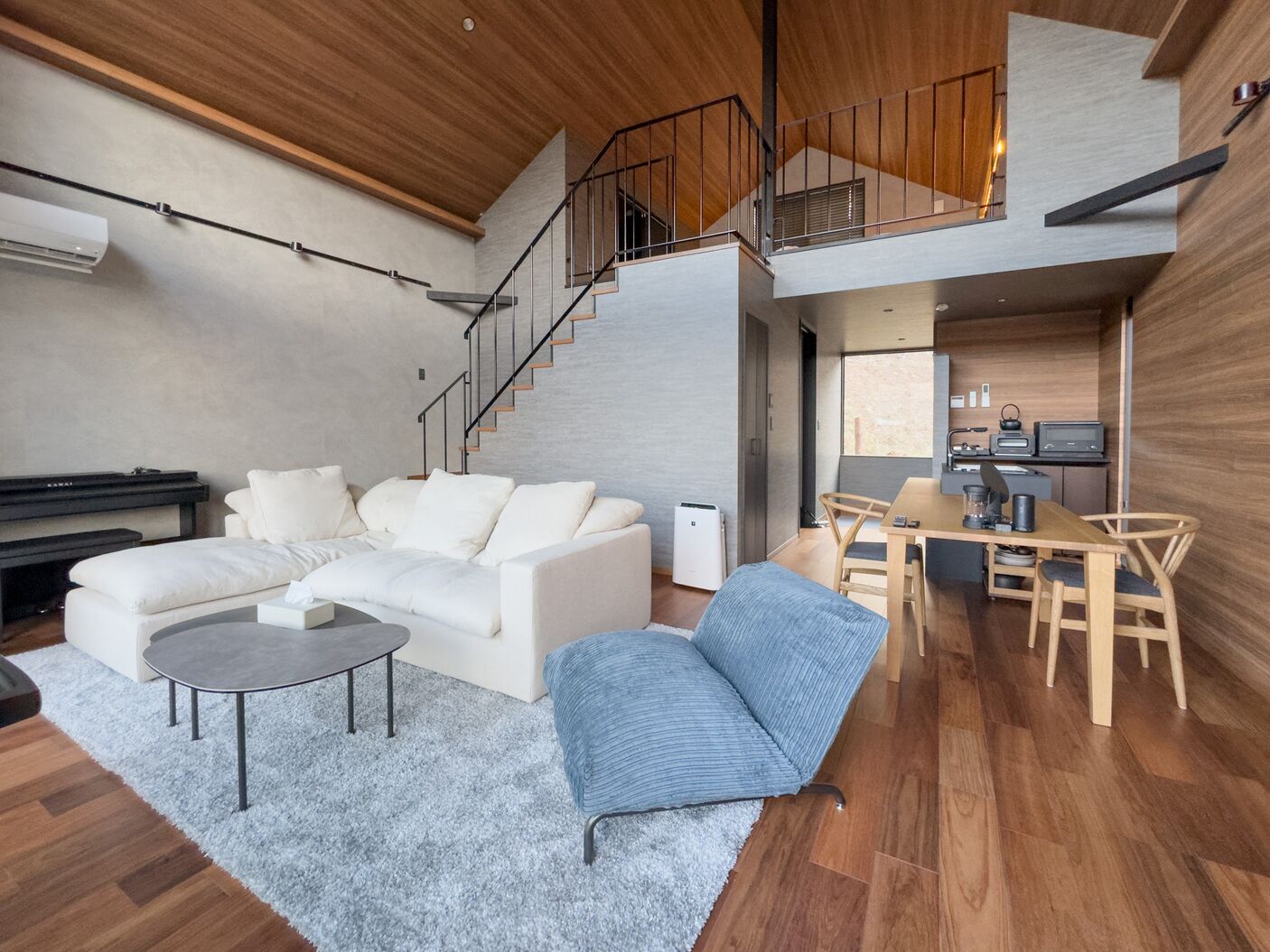 Een moderne woonkamer met een bank, salontafel en een eethoek met stoelen en een tafel.