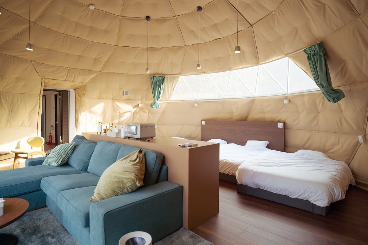 A tent-style room with a sofa, a bed, a small table, and a TV.