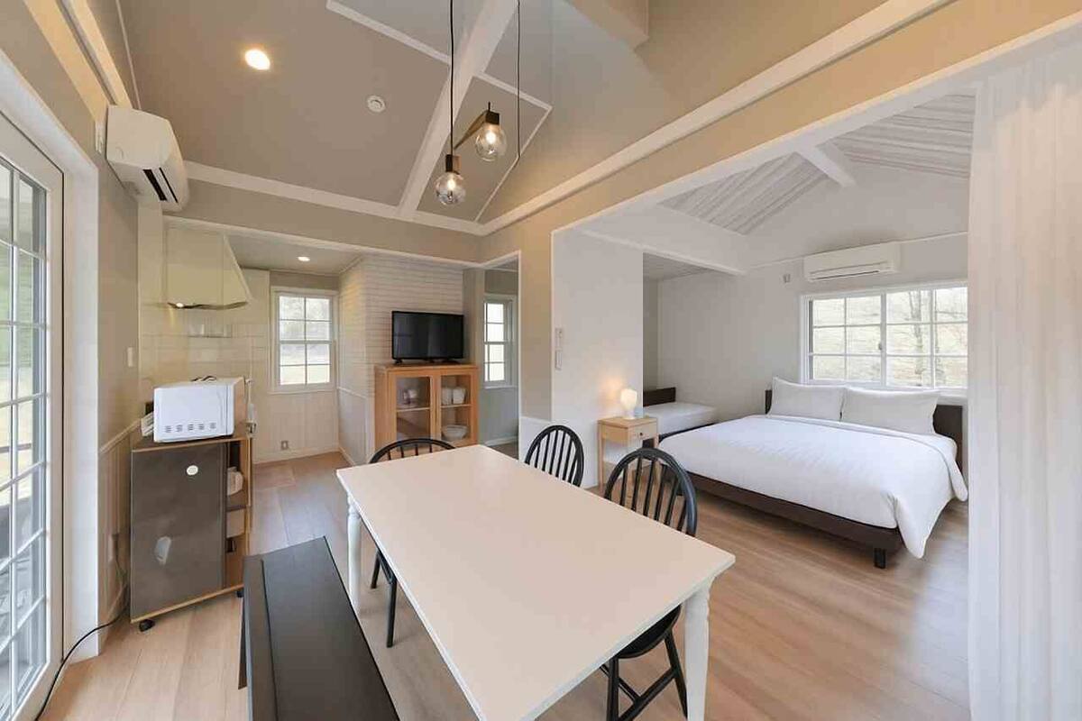 Une chambre d’hôtel moderne équipée d’un lit, d’une table à manger, d’un téléviseur et d’une kitchenette.