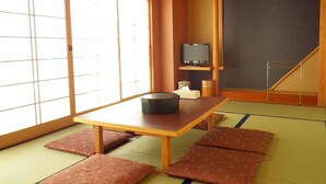 A traditional Japanese room with tatami flooring, a low table with a black container, a television, and a sliding door. - Yao Yume no Mori Yuyukan (Toyama)