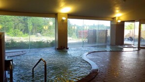 A large indoor pool with clear glass walls, a tiled floor, and a metal pool ladder. - Yao Yume no Mori Yuyukan (Toyama)