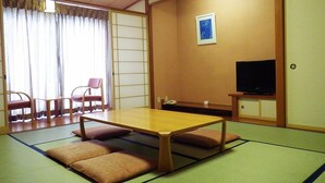 A traditional Japanese-style room with tatami flooring, a low table, cushions, a television, and sliding doors. - Yao Yume no Mori Yuyukan (Toyama)