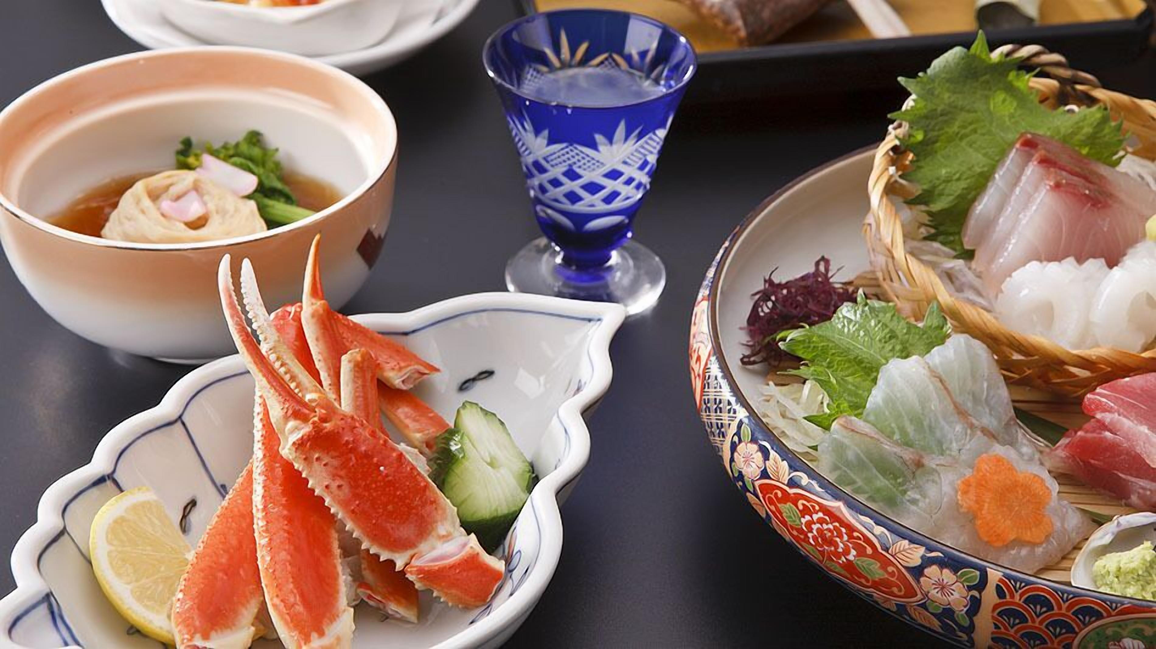 A table with various seafood dishes, a bowl of soup, and a decorative blue glass.