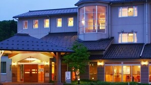 A multi-story hotel with a prominent corner tower, a covered entrance, and large windows. - Yao Yume no Mori Yuyukan (Toyama)
