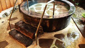 A hot spring with a stone floor, metal steps, and a wooden fence in the background. - Hirayama Onsen Okuyamaga Onsen Ryokan (Yamaga)
