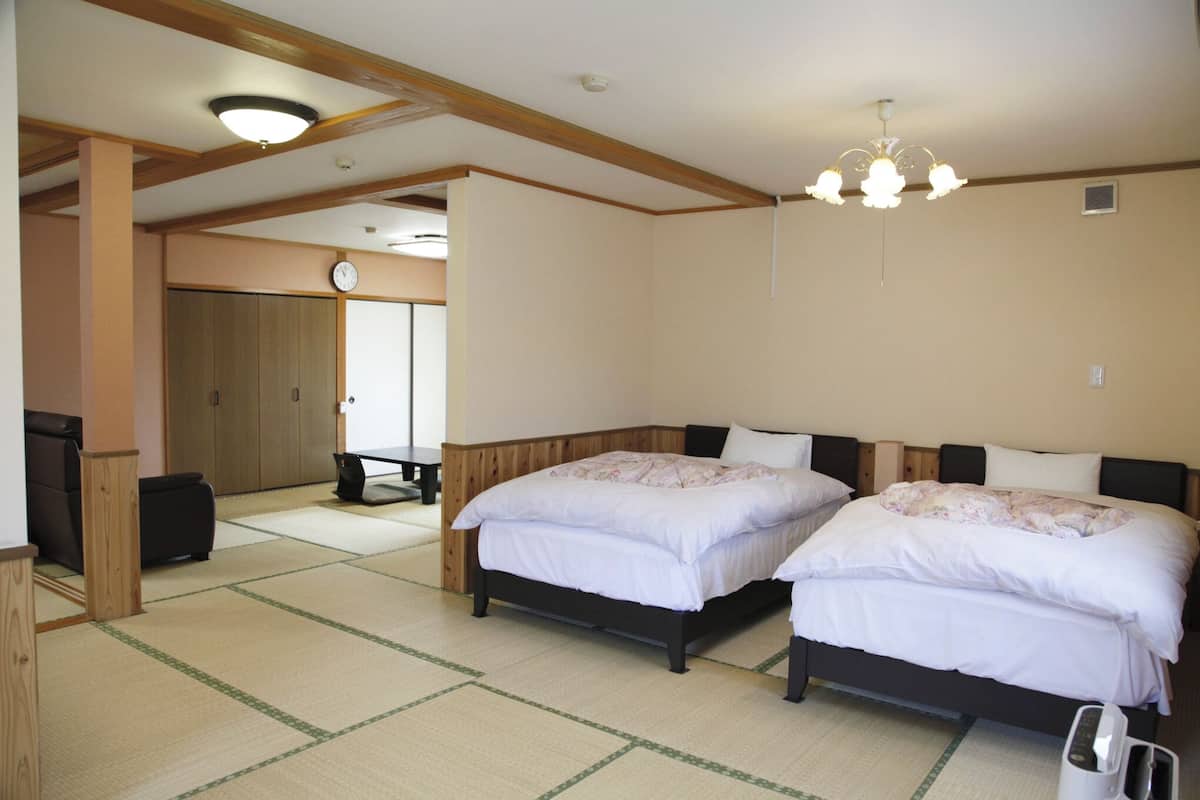 Ein Zimmer mit zwei Betten, einer Holzbalkendecke, einer Uhr und einem Kronleuchter.