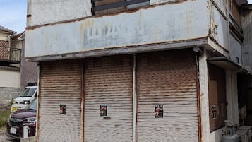 Um prédio de dois andares com uma porta de garagem fechada e uma pequena janela no andar de cima.
