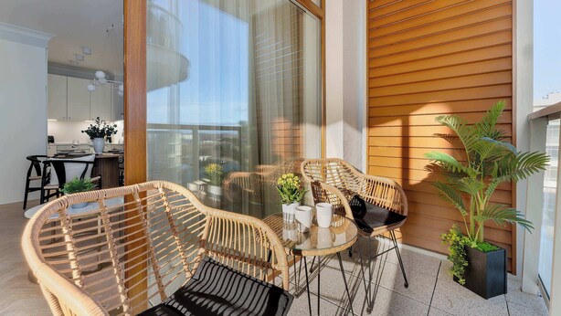 En balkon med fletningsmøbler, et lille bord og en potteplante.