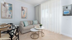 En moderne stue med sofa, spisebord med stole, et lille rundt bord med plante og kunst på væggene.