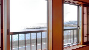 A room with a view of the sea through large windows with metal railings.