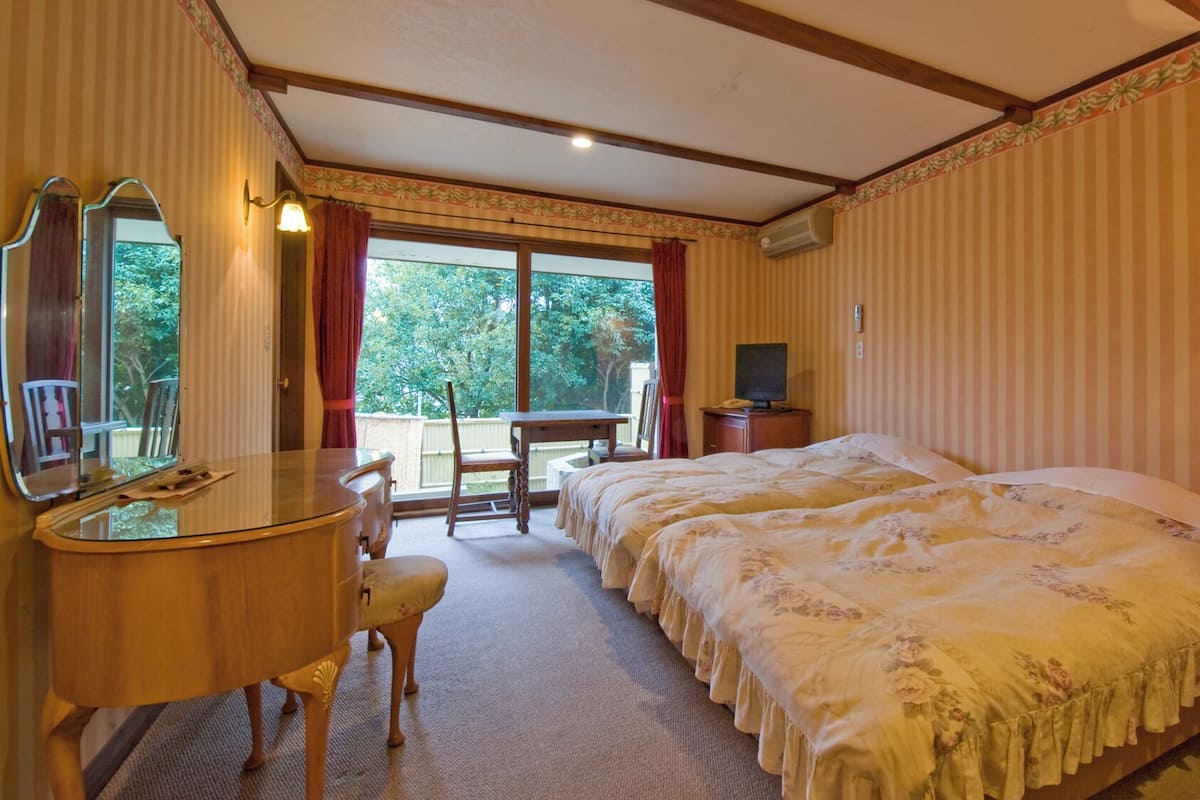 A hotel room with a bed, a desk, a chair, a television, and a window with curtains.