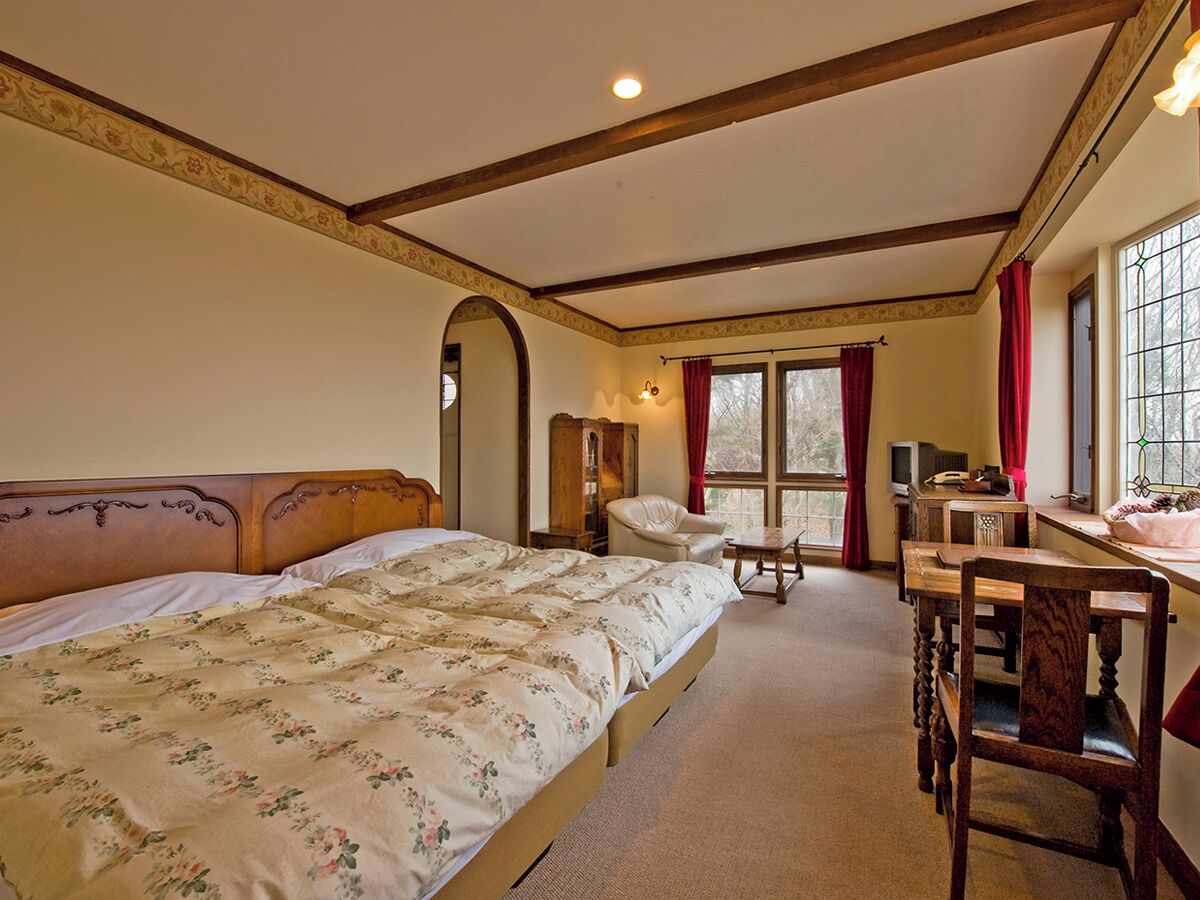 Un dormitorio con cama, escritorio, silla, armario y ventana.
