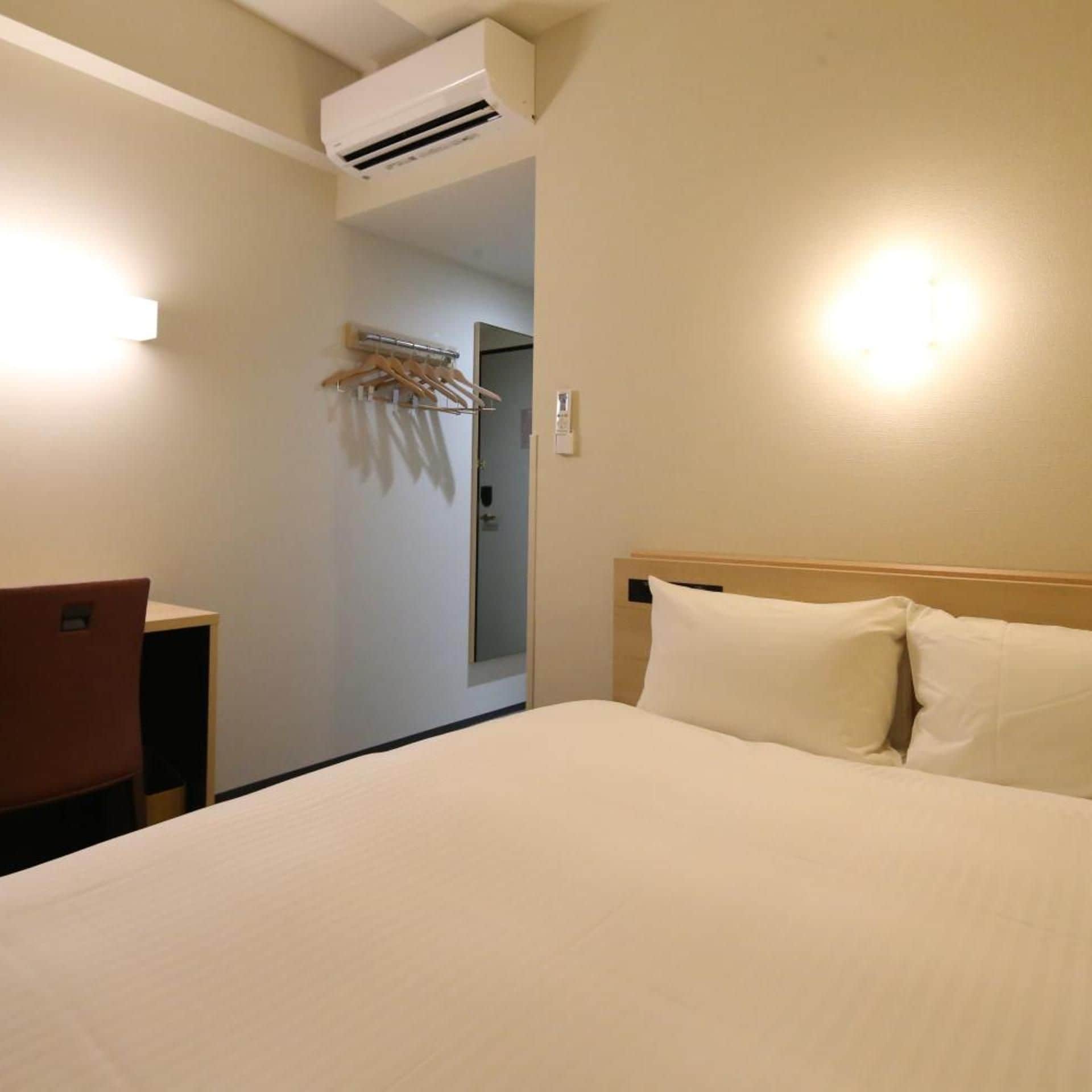 Una habitación de hotel con cama, escritorio y aire acondicionado.