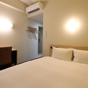 Et hotelværelse med seng, skrivebord og aircondition.